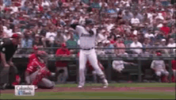 a baseball player is swinging at a ball in front of a crowd of people .