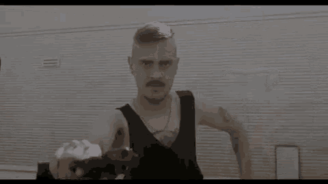 a man with a mustache is flexing his muscles in front of a mirror in a gym .
