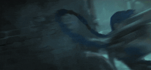 a person with blue hair is laying down in the dark with a green light behind them
