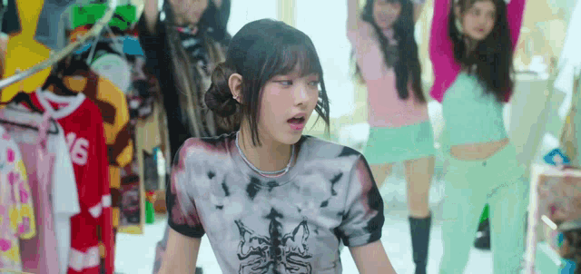 a girl in a tie dye shirt is standing in front of a group of girls in a store .