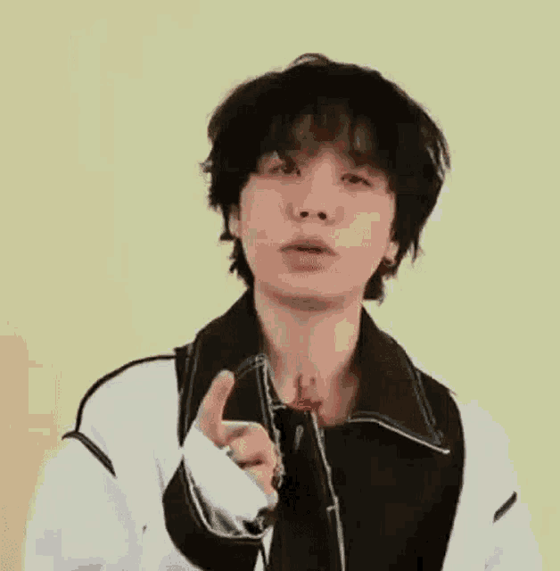 a young man with black hair is pointing at the camera .