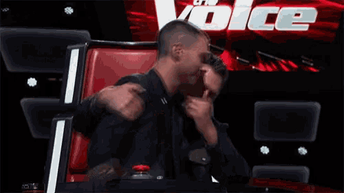 two men are hugging in front of a sign that says voice