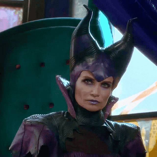 a woman in a purple costume with horns is sitting in a chair