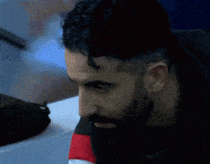 a man with curly hair and a beard is looking down