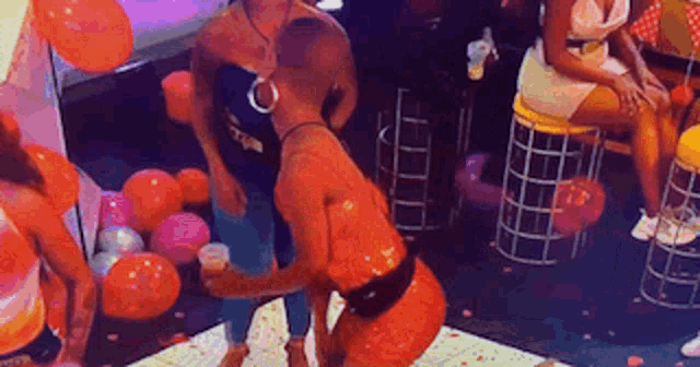a group of women are dancing in a room with balloons on the floor