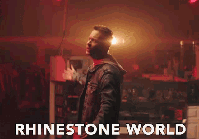 a man singing in a dark room with the words rhinestone world written below him