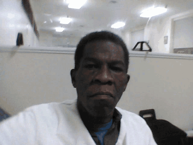 a man wearing a white coat looks at the camera