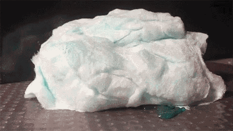 a piece of cotton candy is sitting on a table with a blue liquid coming out of it .