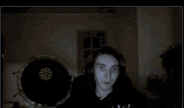 a man wearing headphones is sitting in front of a dart board in a dark room