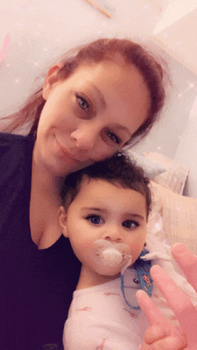 a woman is holding a baby with a pacifier on her mouth
