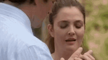 a man is kissing a woman on the cheek while holding her hands .