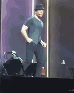 a man in a fedora is dancing on a stage