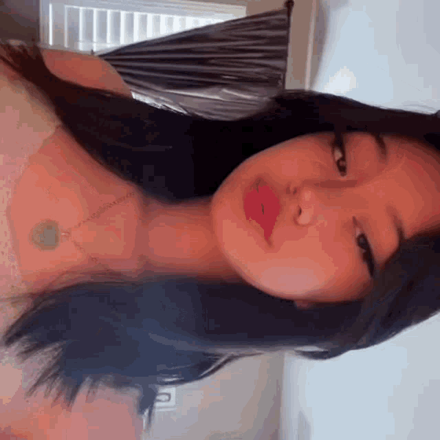 a close up of a woman 's face wearing a necklace and looking at the camera .