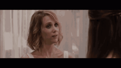 a woman is talking to another woman in front of a window .