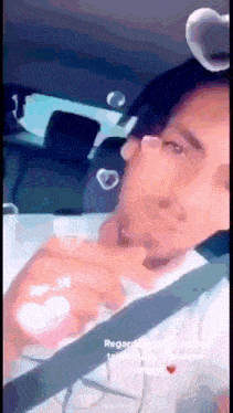 a man wearing glasses is sitting in the back seat of a car with a heart on his head