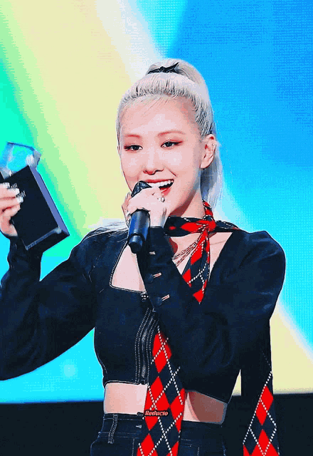 a woman in a plaid scarf holds a microphone