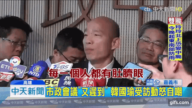 a man in a suit is being interviewed by a group of people with chinese writing