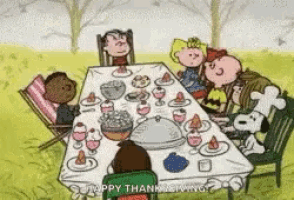 a group of peanuts characters are sitting around a table for thanksgiving .