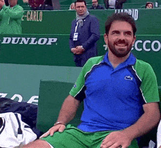 a man in a blue and green shirt sits in front of a dunlop advertisement