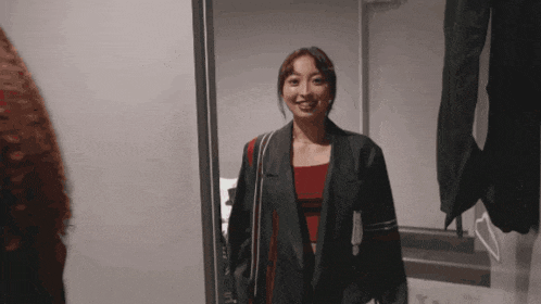 a woman is standing in front of a mirror wearing a jacket