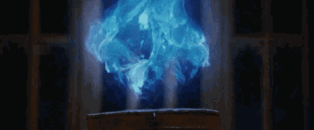 a blue flame is coming out of a book in a dark room