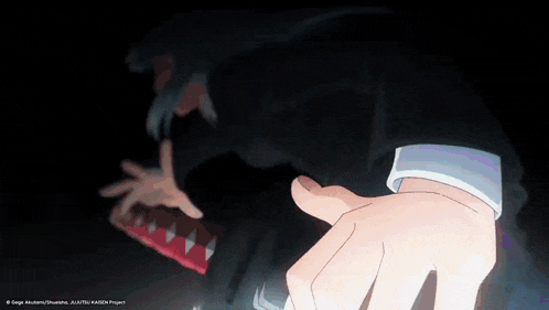 a person 's hand is reaching out towards a monster 's mouth with sharp teeth .