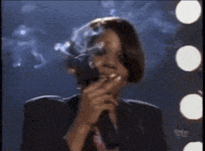 a woman is smoking a cigarette while holding a microphone