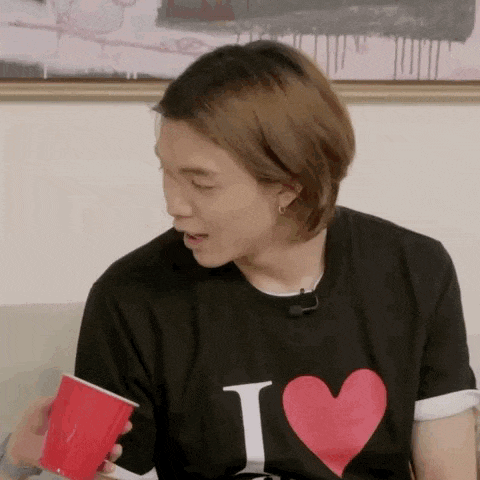 a man is sitting on a couch holding a red cup .
