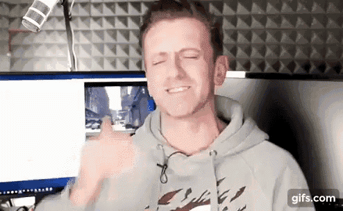 a man in a hoodie is giving a thumbs up in front of a microphone .