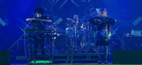 a group of people are standing on a stage playing instruments and dancing .