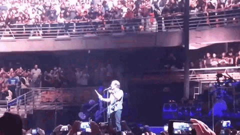 a man is singing into a microphone in front of a crowd of people