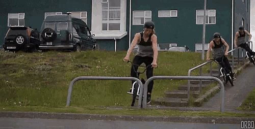 a group of people are riding bicycles down a street and one of them is doing a trick on a railing