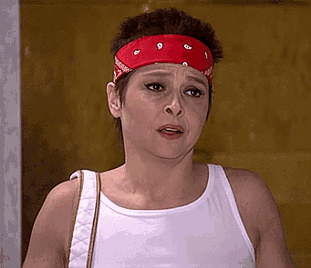 a woman wearing a white tank top and a red headband