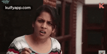 a woman is making a funny face while holding a cell phone in her hand .