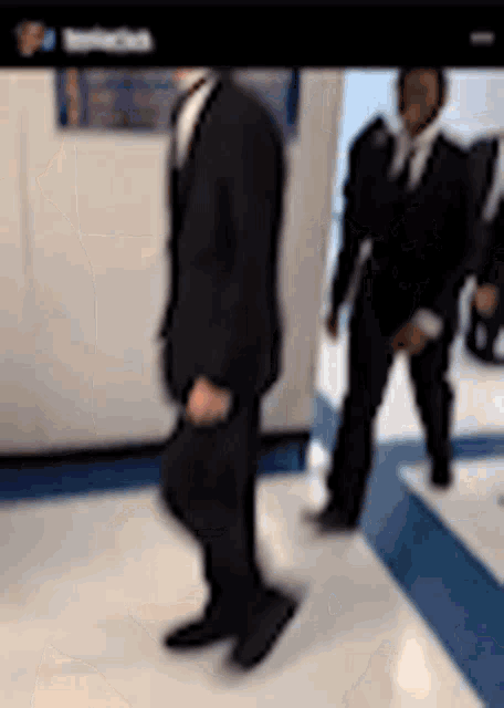 a blurry picture of a man in a suit walking down a hallway