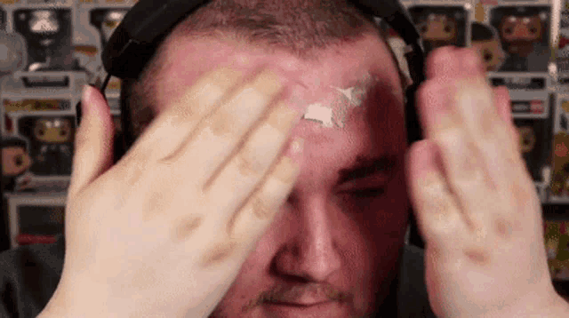 a man wearing headphones has a sticker on his forehead that says ' x ' on it