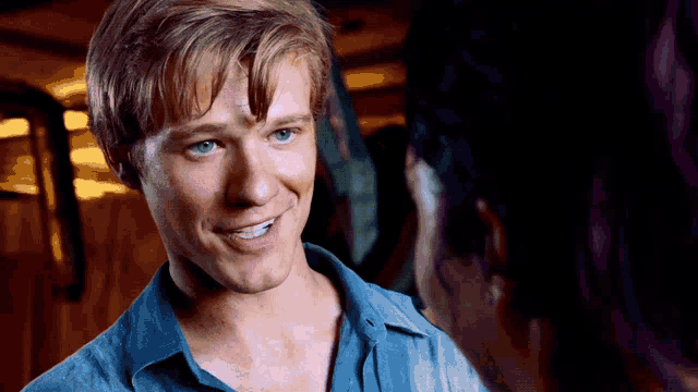 a man with blonde hair and blue eyes looks at a woman