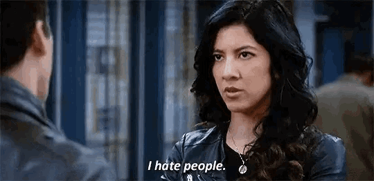 a woman in a leather jacket is talking to a man in a room and saying `` i hate people '' .
