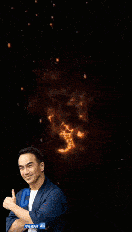 a man giving a thumbs up in front of an explosion