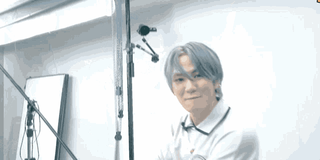 a young man with gray hair is standing in front of a microphone stand