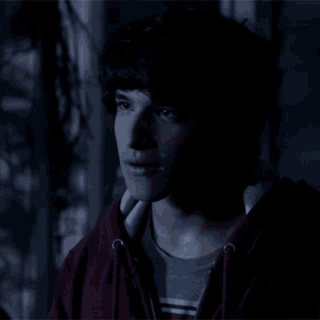 a young man wearing a red hoodie and a striped shirt