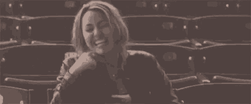 a woman is sitting in a row of seats in a theater laughing .