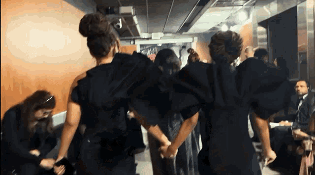 a woman in a black dress holds the hand of another woman