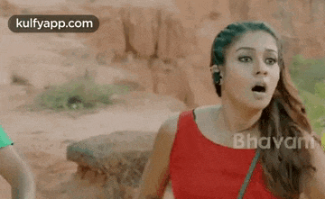 a woman in a red dress is standing in the desert with her mouth open and a surprised look on her face .