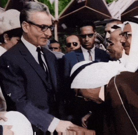 a man in a suit and tie shakes hands with a man wearing sunglasses