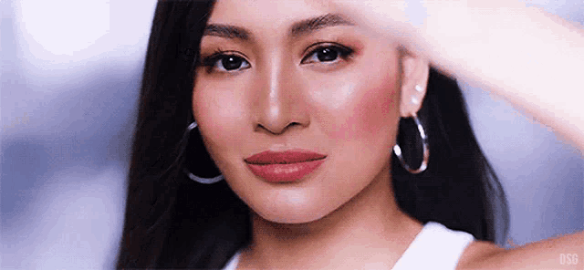 a close up of a woman wearing hoop earrings and a white tank top