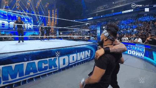two wrestlers are hugging in front of a sign that says mack down