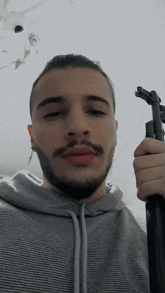 a man with a beard is holding a gun in his right hand