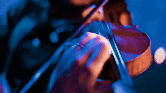 a person is playing a violin in a dark room