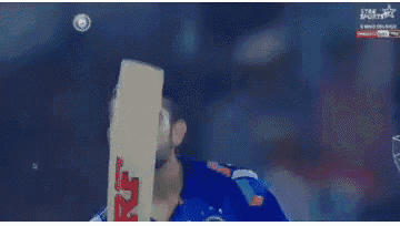 a man with a beard is holding a cricket bat in his hand .